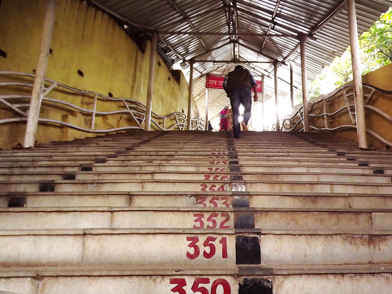 Image is a farbound.net photo showing visitors heading up a flight of stair to the Pahari Baba Mandir - a temple dedicated to Shiva. The temple is located on a hill locally known as Fansi Tungri or the Hill of Hanging.