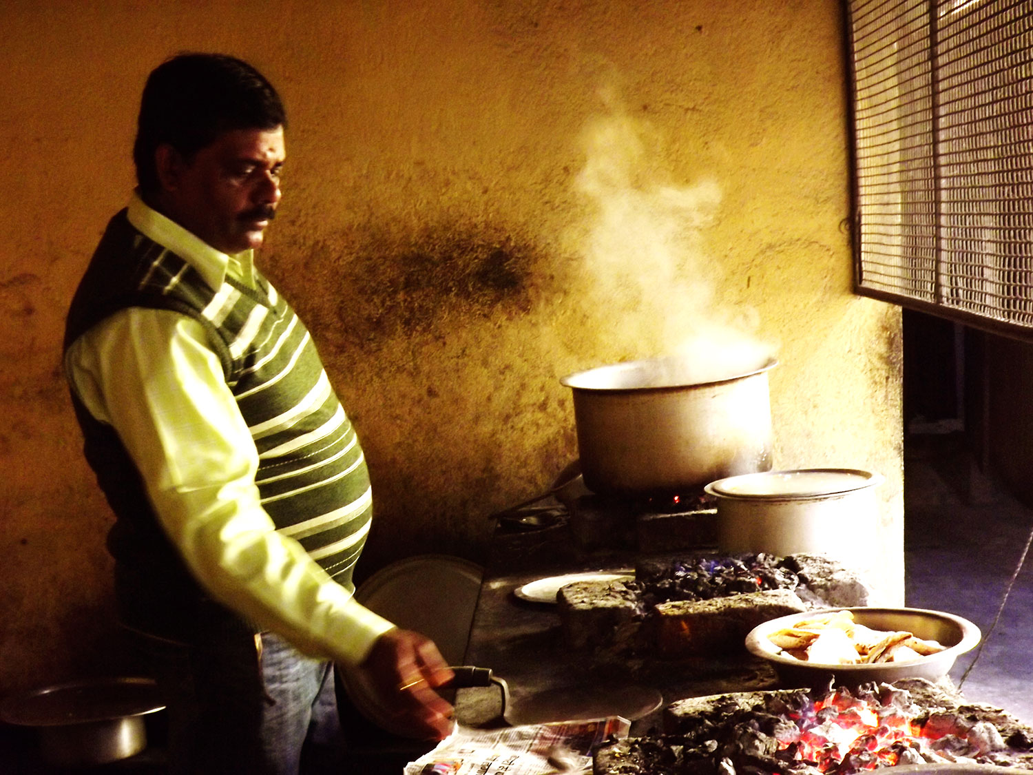 Photo shows a man next to a native clayoven with pits filled with smolder coals in Ranchi, Jharkhand, India