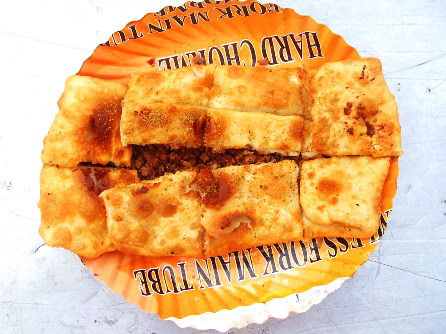 Photo shows a Mughlai Paratha sliced up in square pieces on a paper plate 