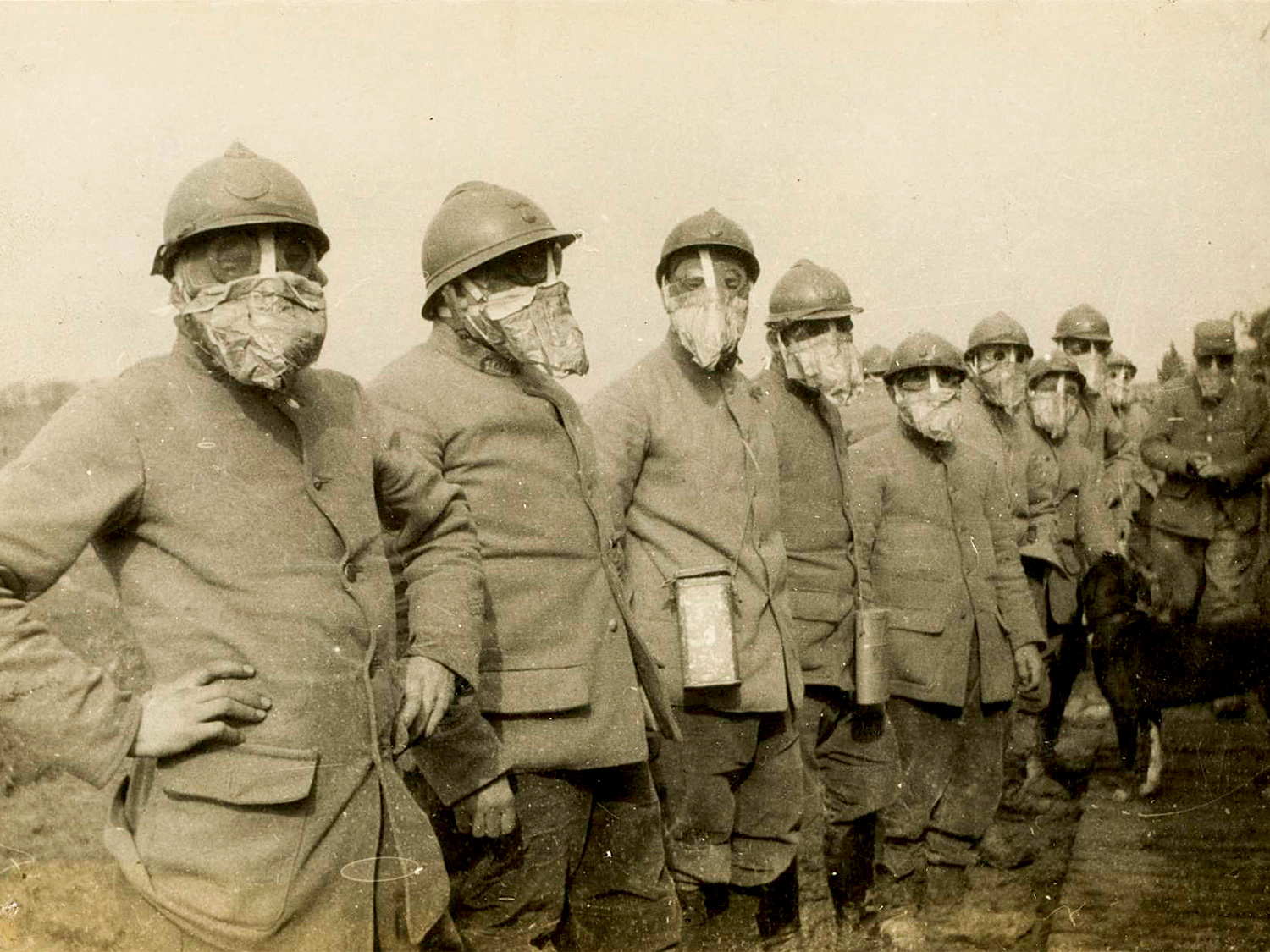 A vinatge photo showing an officer inspecting a line of soldiers weaing the Tampon TN model gas mask in Argonne, France 1916