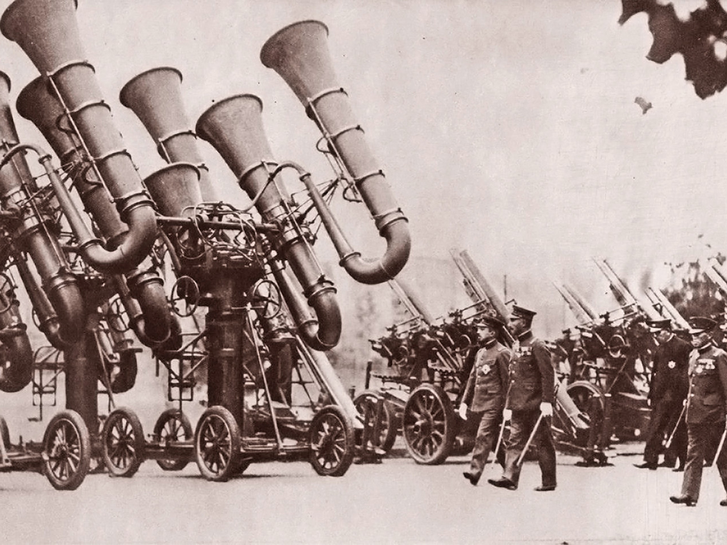 Image shows Japanese emperor Hirohito inspecting a series of Type 90 Japanese sound trumpets placed on trolleys 1930